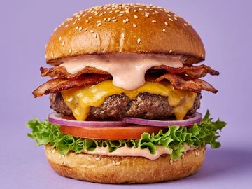 Juicy bacon cheeseburger with lettuce and sauce on a sesame bun.