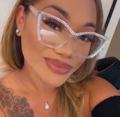 Woman wearing large rhinestone glasses and a floral tattoo on her shoulder.