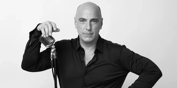 Bald man holding a vintage microphone.
