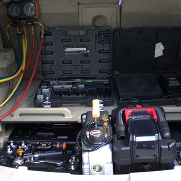 Automotive HVAC diagnostic and repair tools neatly arranged in a vehicle trunk.