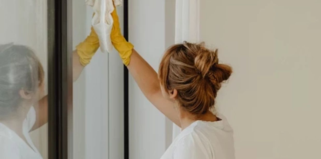 lady in yellow gloves wiping glass with glass cloth