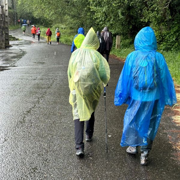 People walking on a rainy day wearing rain ponchos.