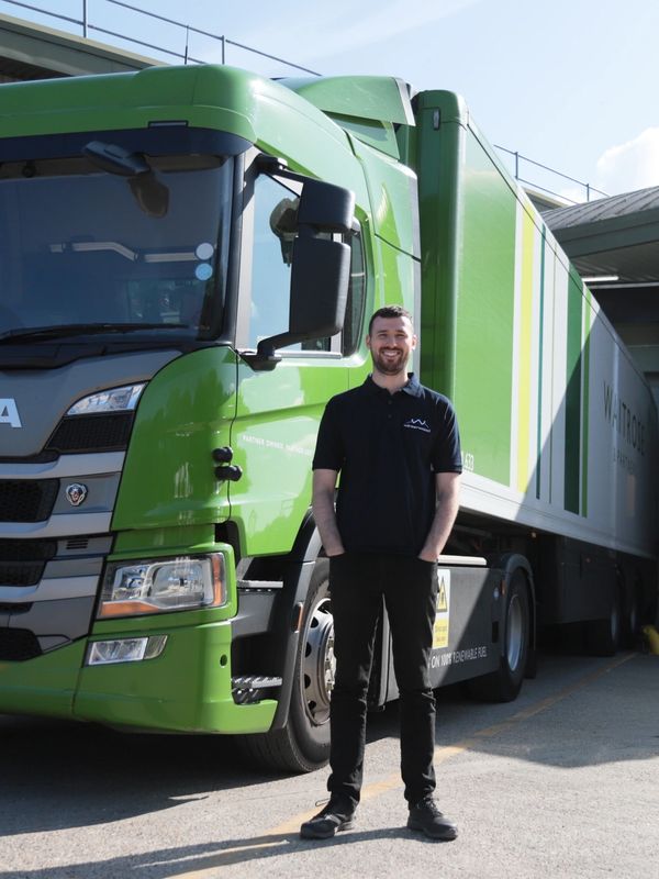 Smiling man standing in front of a green truck.