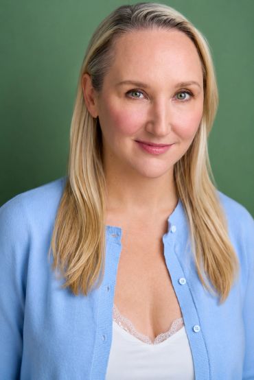 Smiling woman with long blonde hair in blue cardigan.
