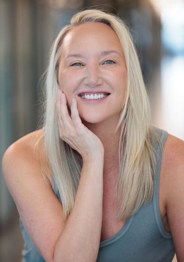 Smiling blonde woman with hand on face.