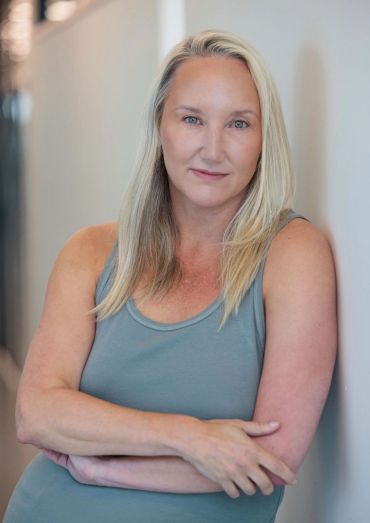 Confident woman leaning against a wall.