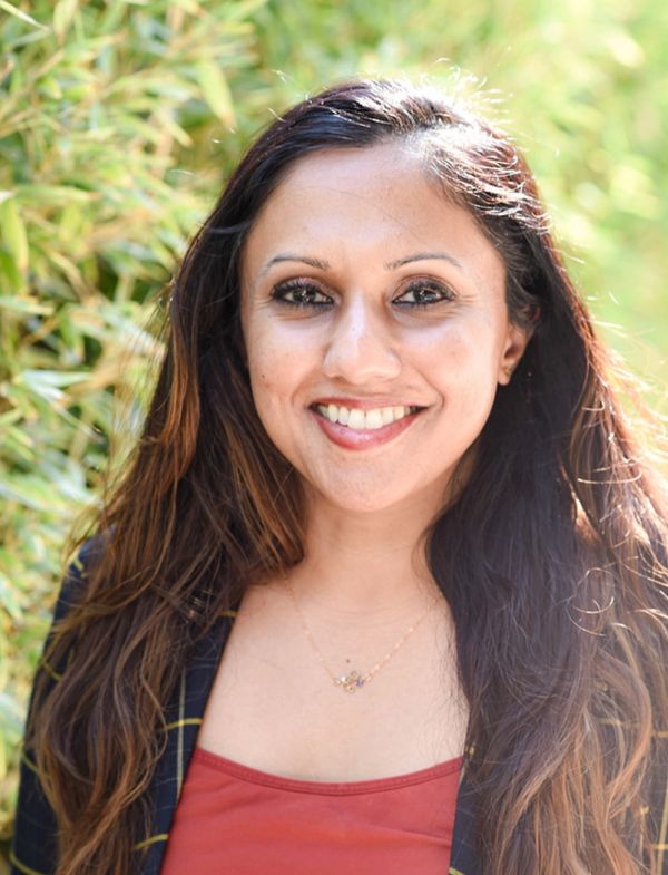 Smiling woman with long hair in natural outdoor setting.