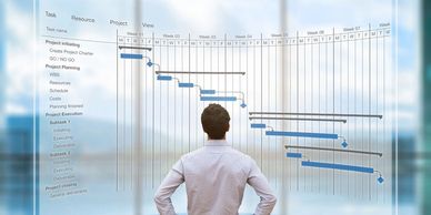 Man reviewing a project Gantt chart on transparent screen.