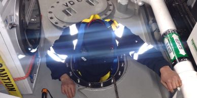 Person emerging from a circular hatchwearing reflective clothing.
