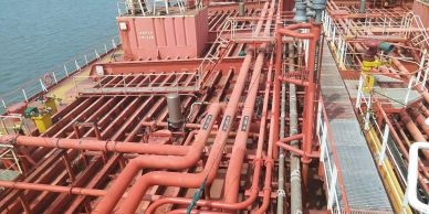 View of red pipes on a ship deck by the water.
