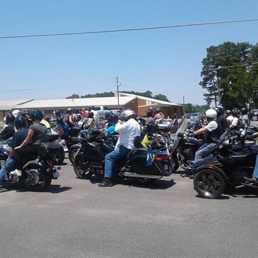 Group of motorcyclists gathered outdoors on a sunny day.