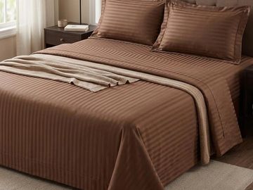 Neatly made bed with brown striped bedding.