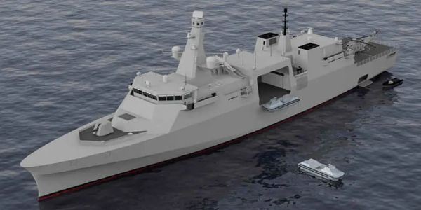 A modern gray naval ship with small boats on water.