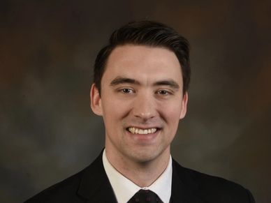 Professional headshot of a smiling man in a suit and tie.