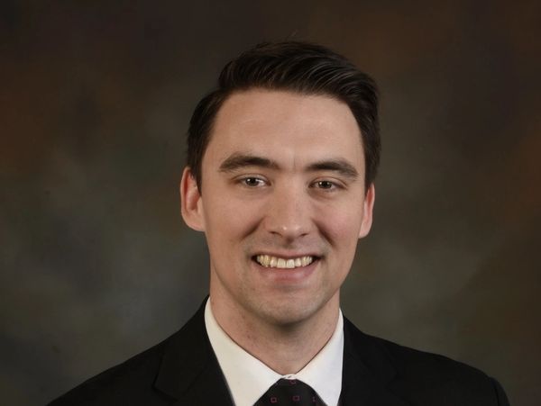 Professional headshot of a smiling man in a suit and tie.