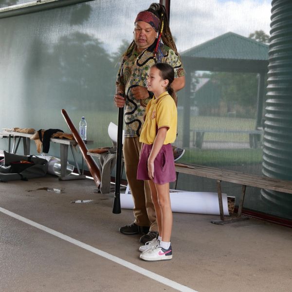 A man with traditional attire and a young girl standing together indoors.