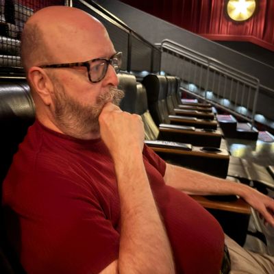 Man in a theater sitting and thinking.