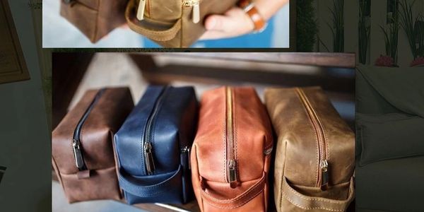 Four leather toiletry bags in different colors lined up on a surface.