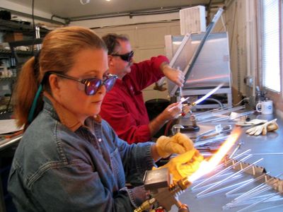 Students melting glass on bench mounted torches at Striking Art Studio.