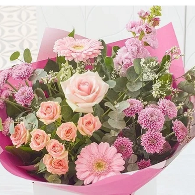 A vibrant bouquet of pink and purple flowers wrapped in pink paper.