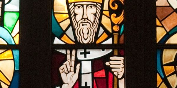 Stained glass window depicting a saint with a staff and a halo.