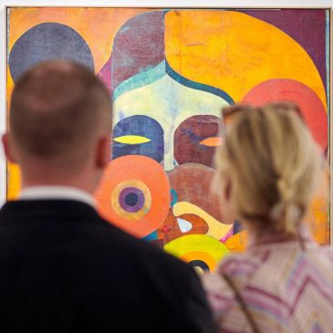 Two people viewing a colorful abstract painting.