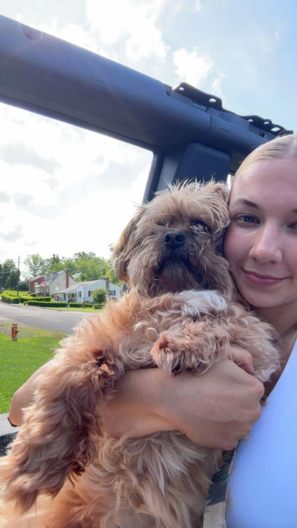 Young woman hugging a fluffy brown dog outdoors.