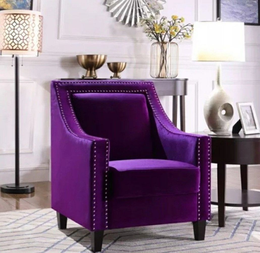 Royal purple chair in a white and natural toned room with a side table and modern decor .