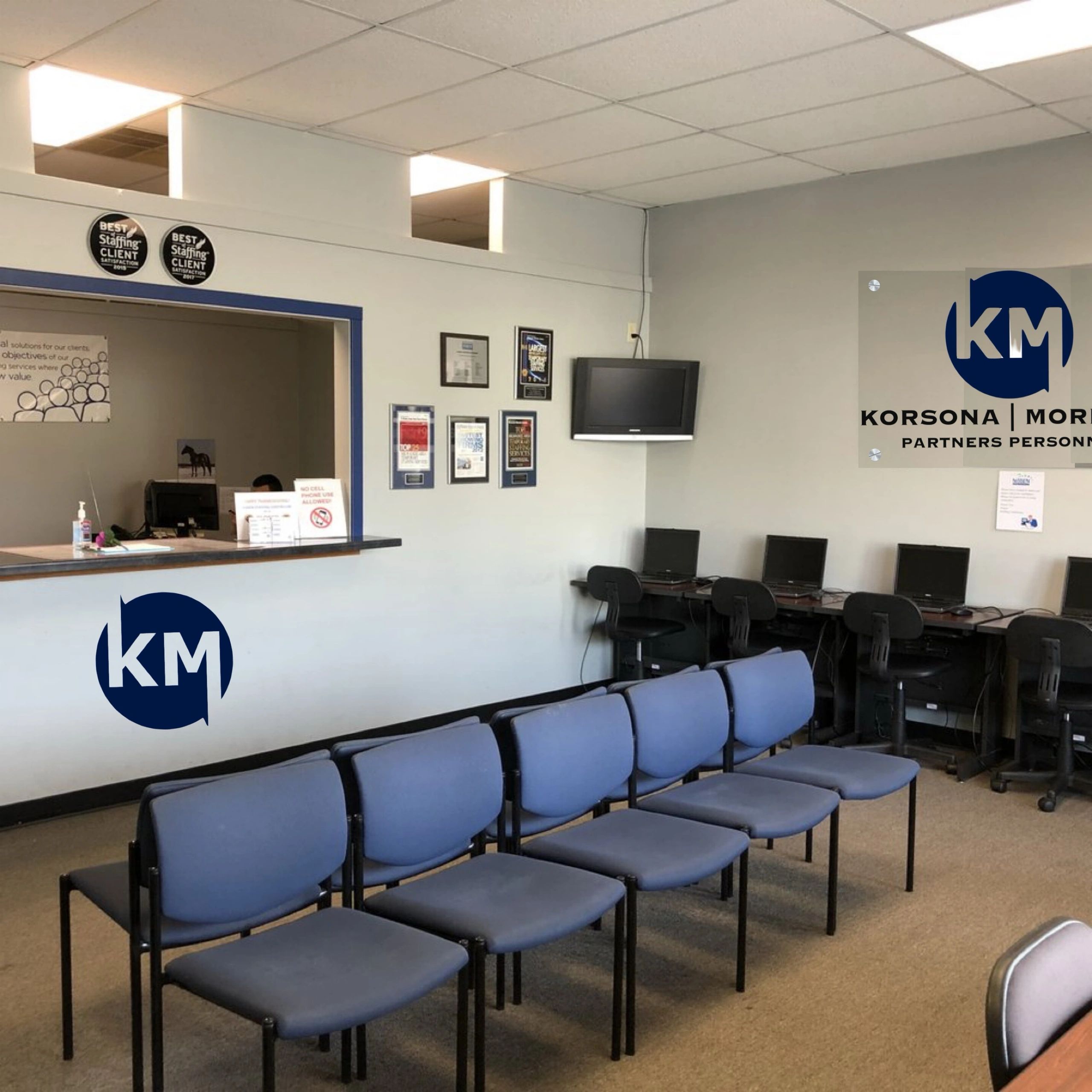 Office waiting area with blue chairs and computer stations.