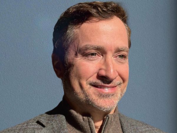 Smiling man with short hair and light stubble.