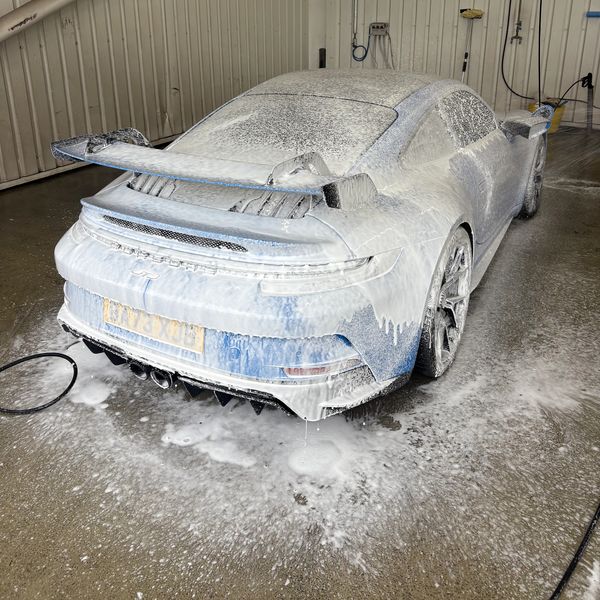 A Porsche 911 GT3 covered in thick foam during a car wash.