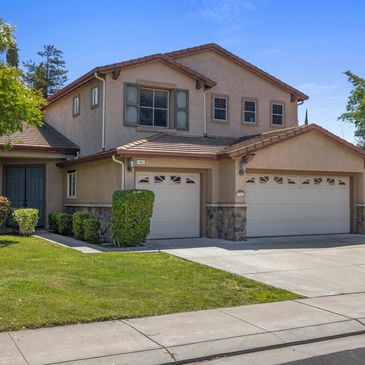 Two-story suburban house with a three-car garage and well-maintained lawn.