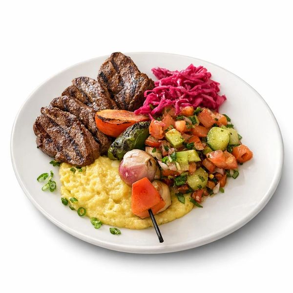 Grilled steak with mashed potatoes, vegetable skewer, cucumber tomato salad, and shredded red cabbage.
