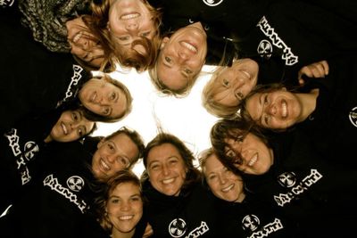 Group of friends smiling in a circle wearing matching hoodies.