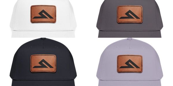 Four caps in white, gray, black, and lavender with a brown leather patch logo.