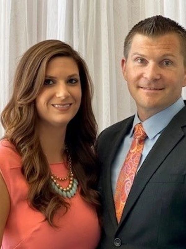 A smiling couple dressed formally, posing for a photo.
