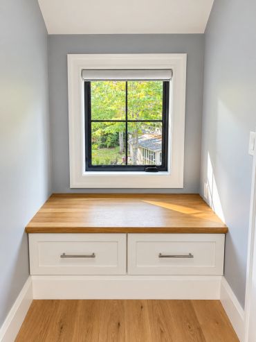 Window seat with storage drawers under a bright window.