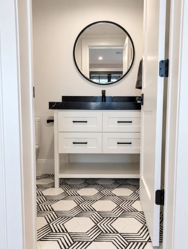 Modern bathroom with black and white geometric floor tiles.