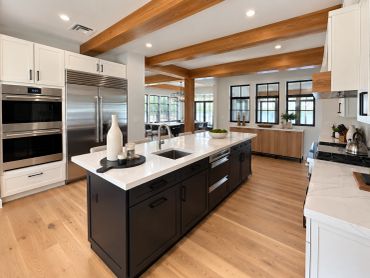Modern kitchen with wooden beams and large island.