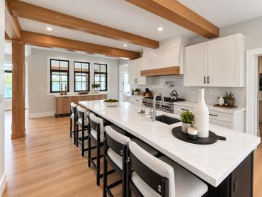 Modern kitchen with white countertops and wooden beams.