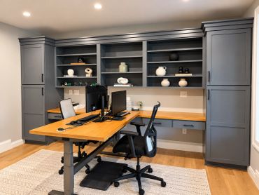 Modern home office with gray cabinets and wooden desk.