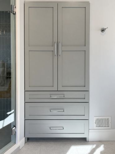 Tall gray cabinet with multiple drawers and doors.