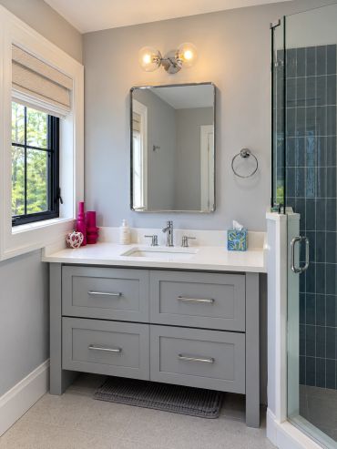 Modern bathroom vanity with gray drawers and a mirror.