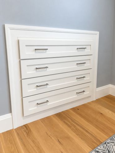 Wall-mounted white cabinet with four drawers and silver handles.