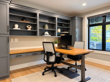 Modern home office with wooden desk and ergonomic chairs.