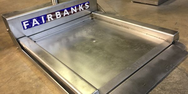 Stainless steel Fairbanks platform scale on a concrete floor.