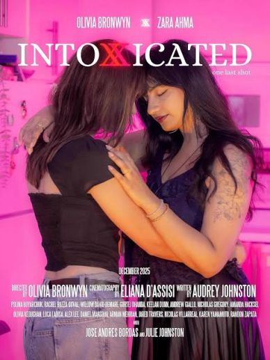 Two women embracing tenderly under pink lighting.