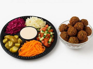 Falafel party platter with fresh salads, pickles, tahini sauce, and crispy falafel – and tasty.