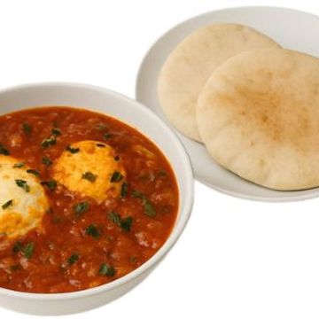 Savory shakshuka with poached eggs in rich tomato sauce, served with warm, fluffy pita bread.