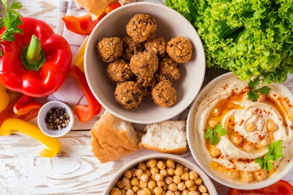 Vegan Mediterranean platter with falafel, hummus, chickpeas, lettuce, peppers, and fresh bread.
